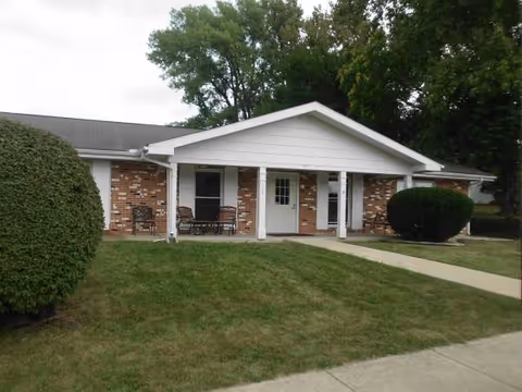 Exterior of a brick senior living facility with a front porch and seating.