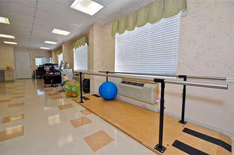 An indoor corridor features parallel bars and exercise equipment along the wall.