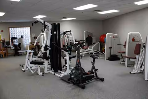 Interior of a senior living gym at Cokato Manor with weight machines and cardio equipment.