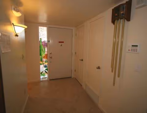 Interior hallway of a senior living facility with doors and a stained-glass panel