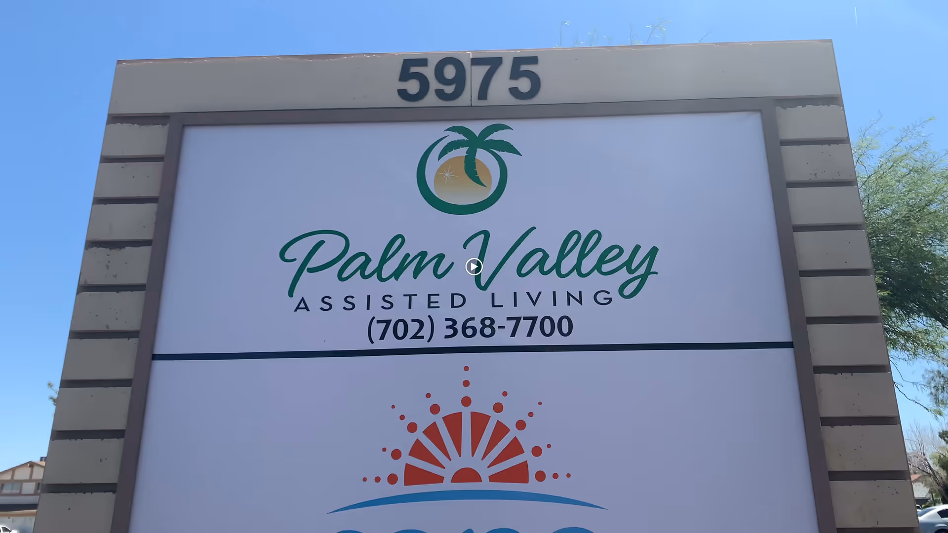 Outdoor sign for Palm Valley Assisted Living with a phone number (702) 368-7700, located at address number 5975, under a clear blue sky.