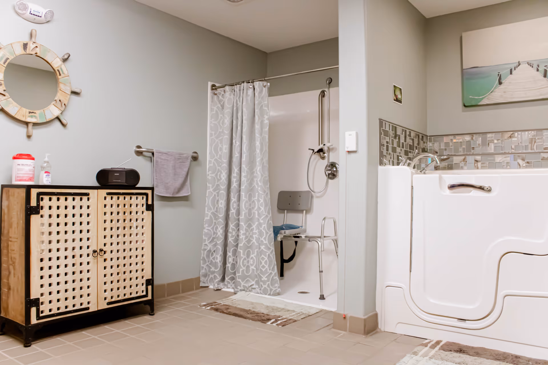 Accessible bathroom with a walk-in tub, roll-in shower with a shower chair, storage cabinet and decorative mirror.