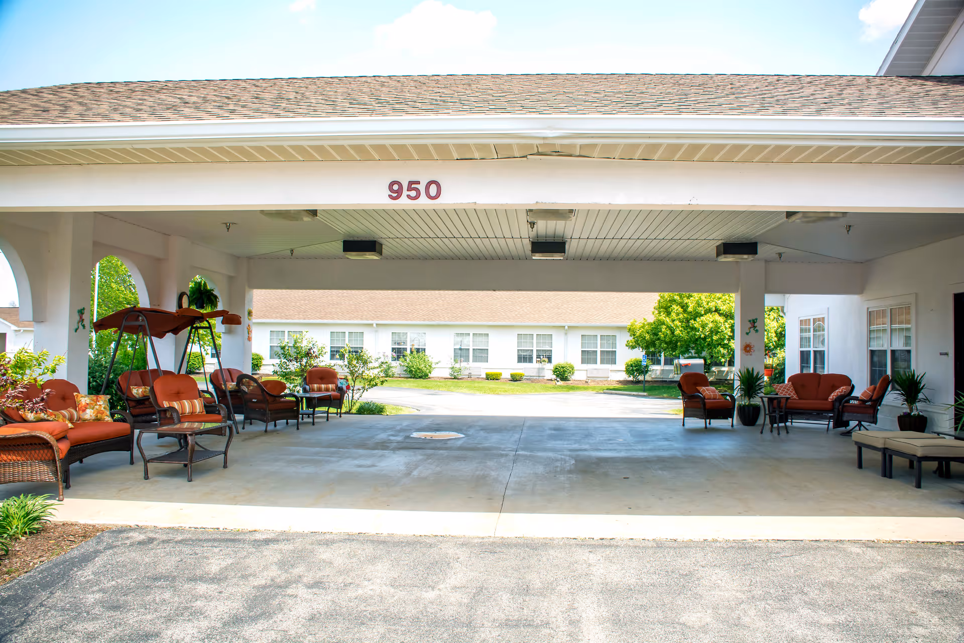 Covered porte-cochère entrance of a retirement community with outdoor seating and the number 950 displayed.
