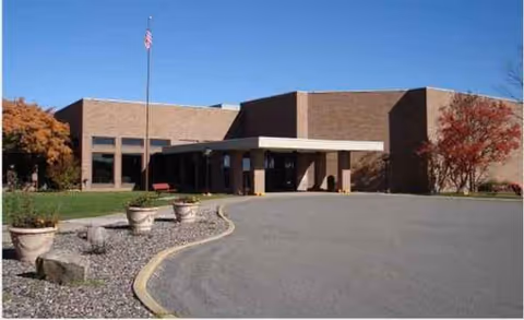 Norwood Health Ctr building exterior with entrance, flagpole, and parking lot.