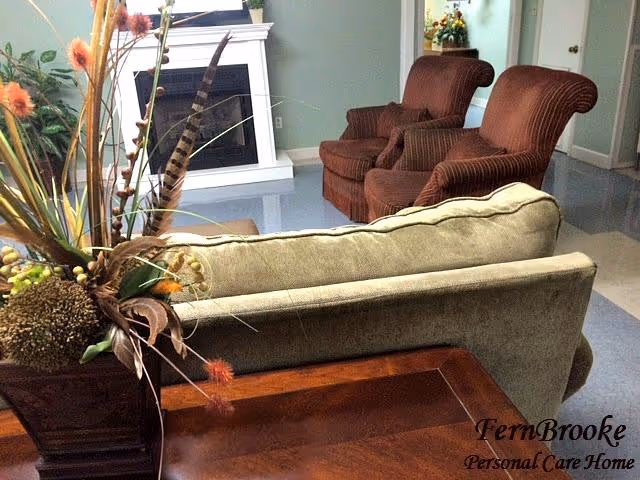 Seating area with a sofa, two upholstered armchairs, a fireplace and a decorative plant arrangement in a cozy living room.