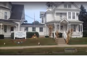 White Victorian-style retirement home with a front porch, lawn sign, and steps decorated with corn stalks.