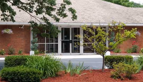 Tremont Health & Rehabilitation Center entrance with glass doors and trimmed shrubs.