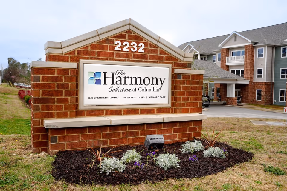 Brick entrance sign reading "The Harmony Collection at Columbia" with address 2232 in front of the senior living building.