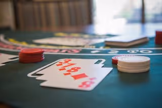 Close-up view of a blackjack table with playing cards and red and white poker chips placed on the green felt surface.