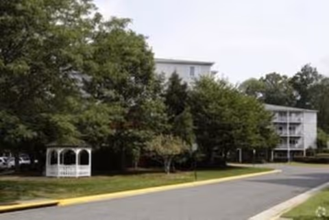 Exterior view of Forest Glen II with trees, a gazebo, and a driveway in front.