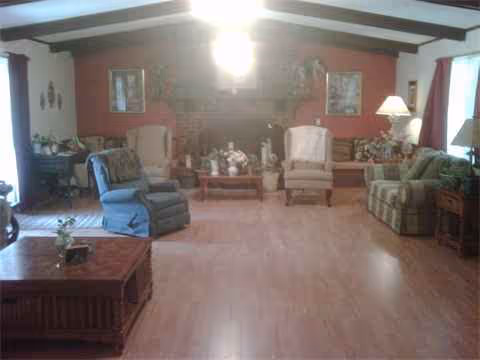 A cozy senior living lounge with couches, chairs, and a fireplace in a spacious room.
