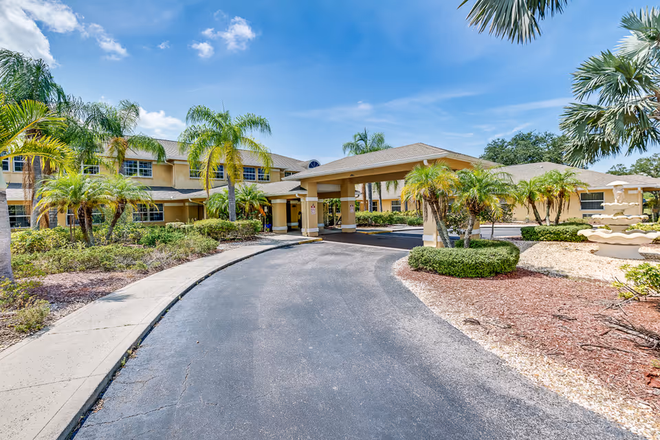 Sunny exterior of Escondido Senior Living showing a porte-cochere, driveway, and palm trees.