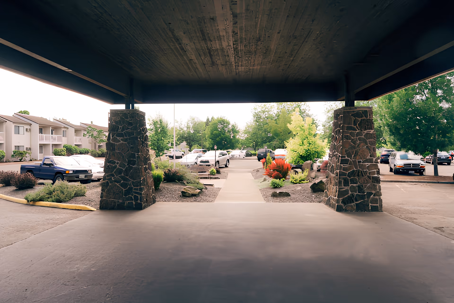 View of the entrance to Churchill Estates, featuring stone pillars and landscaped gardens, with parked cars in the background.