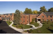 Aerial view of brick senior living buildings with curved walkways, landscaped lawns, and trees.