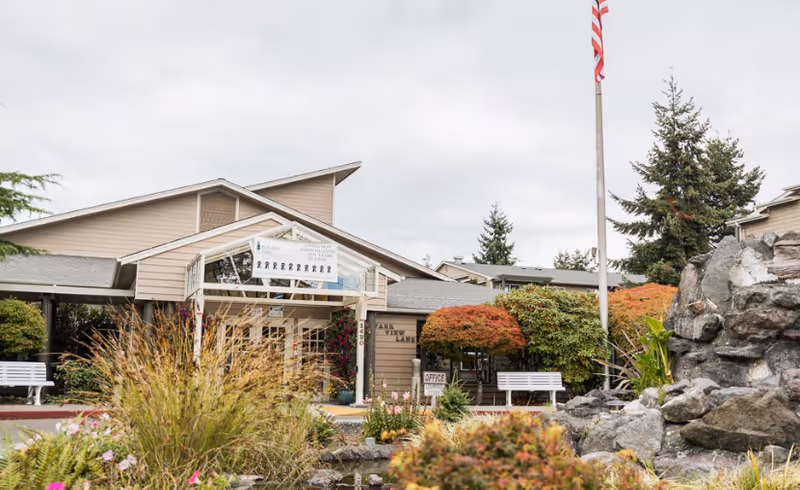 Exterior view of Village Concepts of Port Angeles Park View Villas entrance with landscaping and benches.