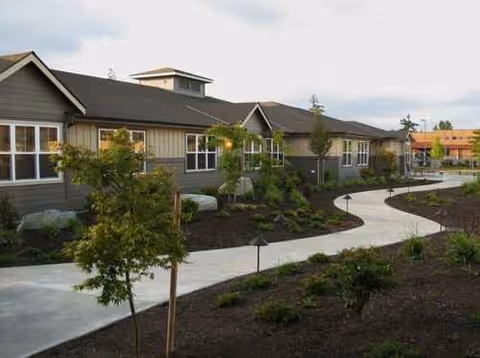 Exterior view of a senior living campus with curved walkway and landscaped front.
