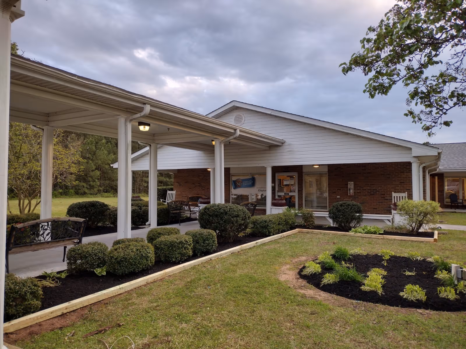 Exterior view of Clayton Rehabilitation and Healthcare Center with covered walkway and landscaped garden.