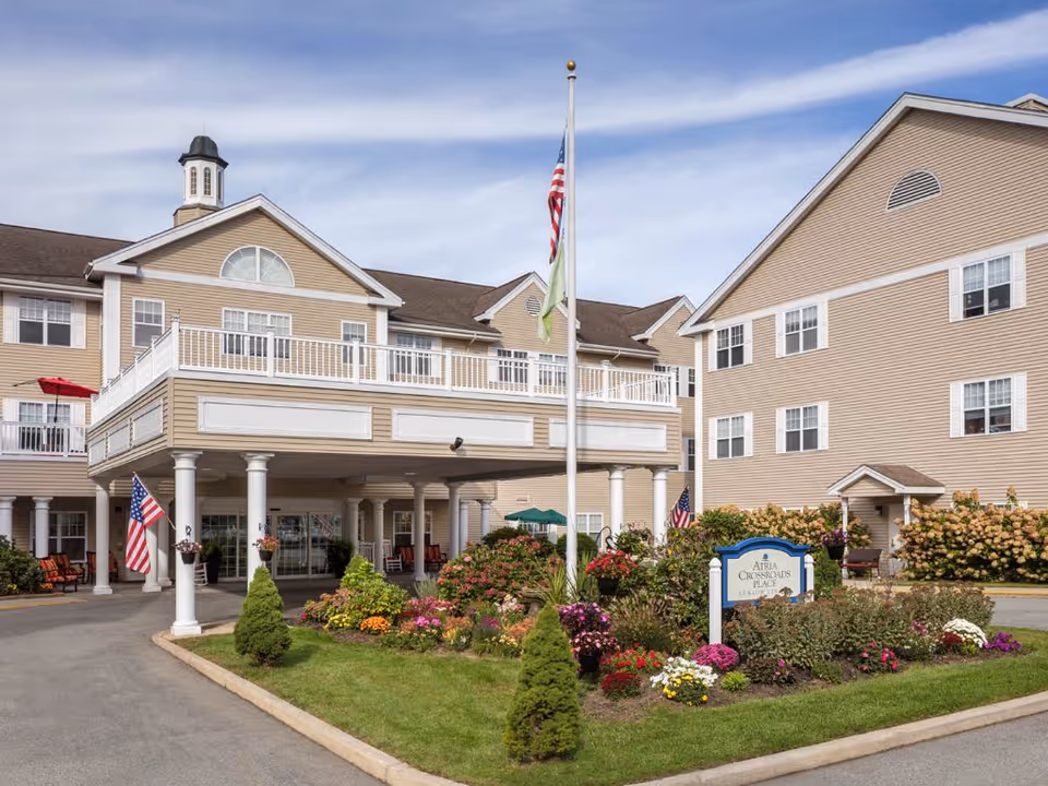 Exterior view of Atria Crossroads Place with a landscaped entrance and flagpoles