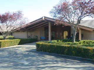 Front exterior of Madonna Gardens Assisted Living and Memory Care with a covered entry and benches.