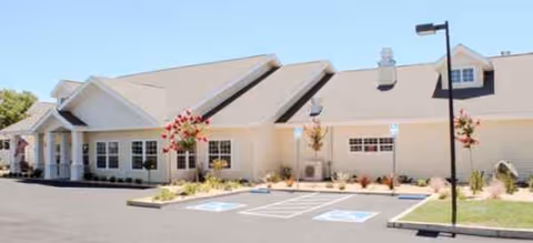 Single-story senior living building front with parking spaces and manicured landscaping.