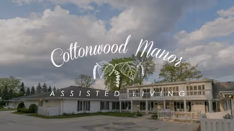 Front exterior of Cottonwood Manor Assisted Living building under a cloudy sky.