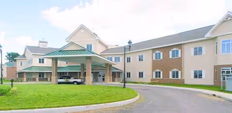 A large senior living facility with a covered drop-off entrance and beige facade.
