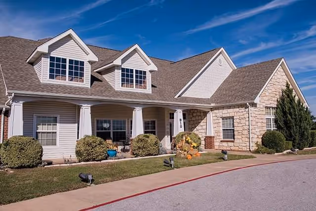 Exterior front of a senior living facility with shrubs and stone accents.