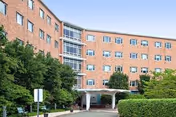 Front view of St Joseph's Center, a brick senior living building with entrance and trees.