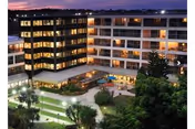 A multi-story illuminated senior living building overlooking a landscaped courtyard at dusk.
