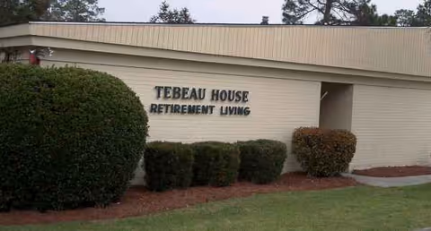 Exterior view of Tebeau House Retirement Living sign on wall.
