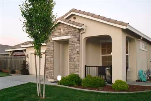 Exterior view of Blossom Ridge Care Home with stone-entry and manicured landscaping.