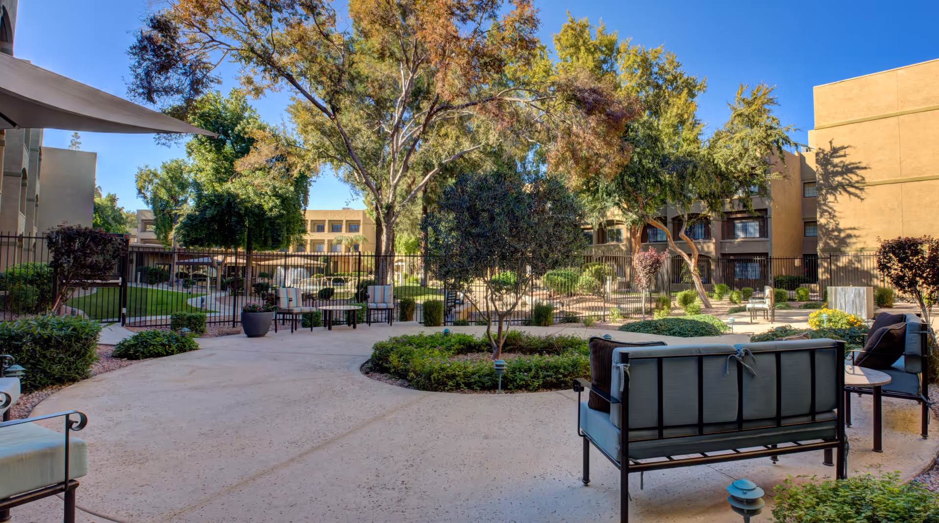 An outdoor courtyard with seating, trees, and landscaped paths at Thunderbird Senior Living.