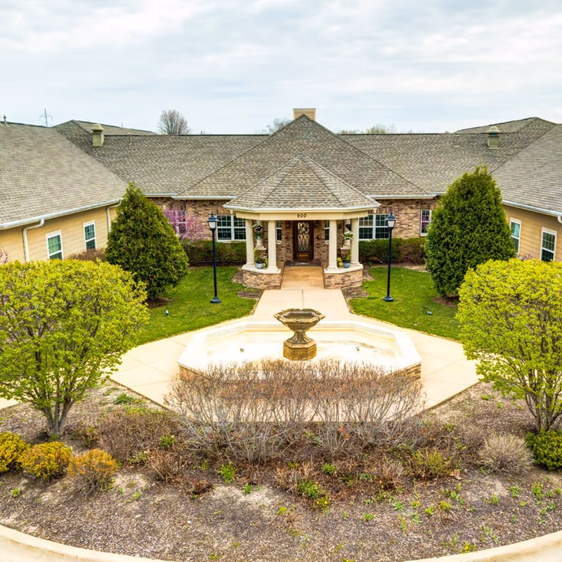 Exterior view of Longevity of Granite City showing the front entrance with a fountain and landscaped grounds.