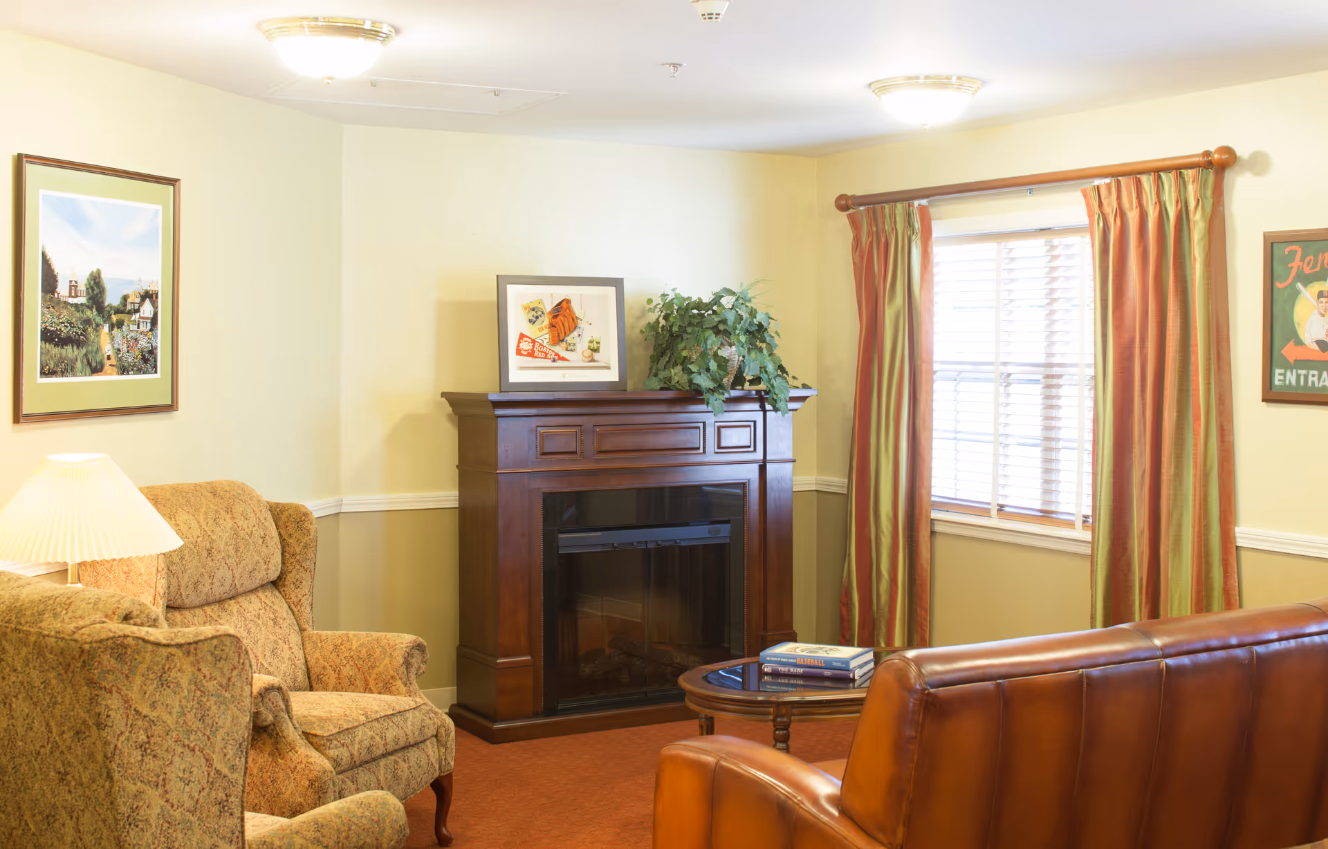 Cozy living room with upholstered armchairs, a leather sofa, a wooden fireplace mantel, framed art, and a window with curtains.