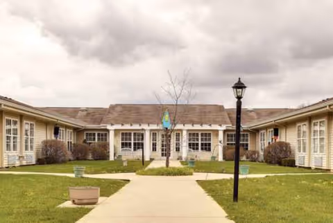 Exterior of Trustwell Living at Settlers Place, a single-story building with walkway and lawn.
