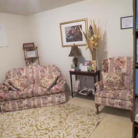 Two floral sofas and a chair arranged in a cozy living room with a side table.