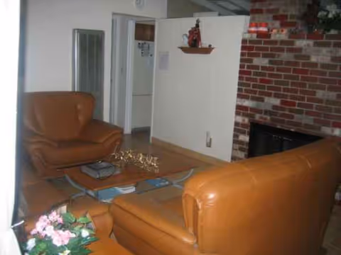 Cozy living room with brown leather sofas, a brick fireplace, and a coffee table.