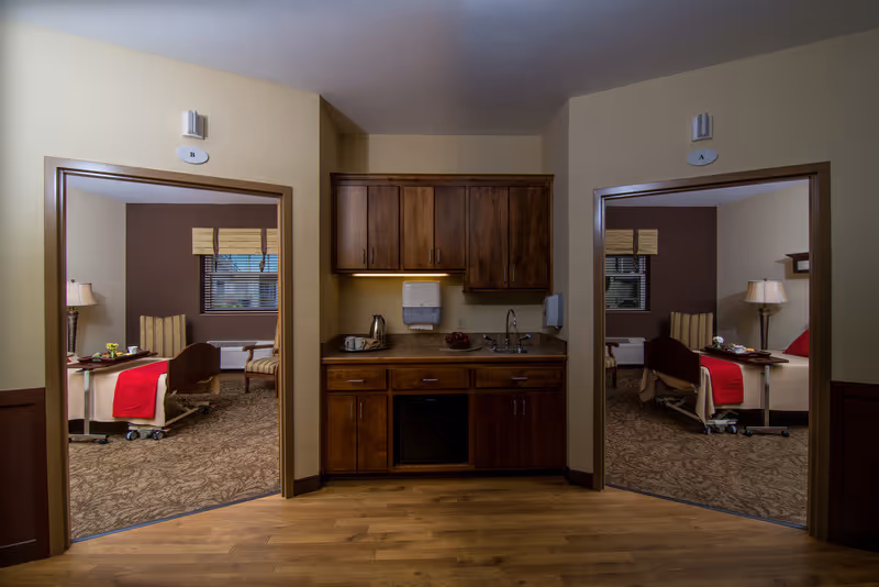 Interior view of a senior facility corridor with a central kitchenette and two patient rooms visible on either side.