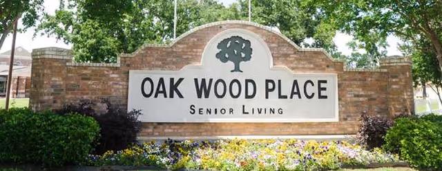 Outdoor brick sign for Oak Wood Place Senior Living with landscaping