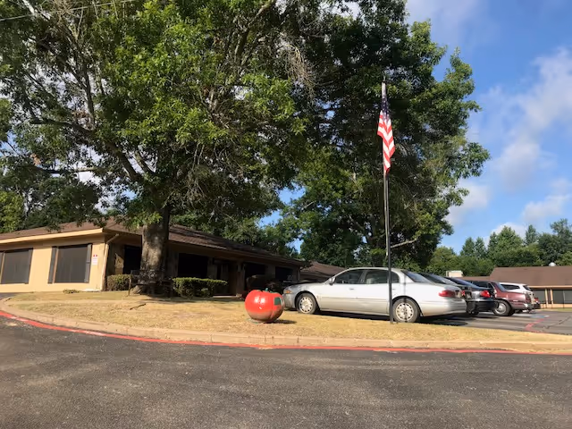 Exterior view of Twin Oaks Health & Rehabilitation Center with trees and cars.