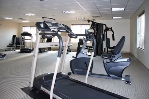 Exercise room with treadmills, a recumbent bike, and strength-training equipment in a bright interior space.