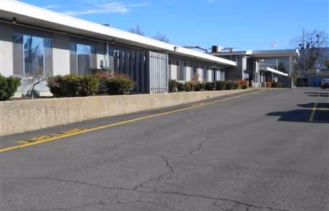 Exterior view of Hearthstone Nursing and Rehabilitation Center with a parking lot and shrubs.
