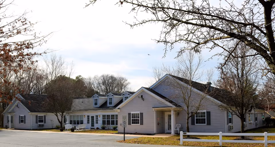 Exterior view of Arcadia Assisted Living of Denton, a single-story residential facility with trees.