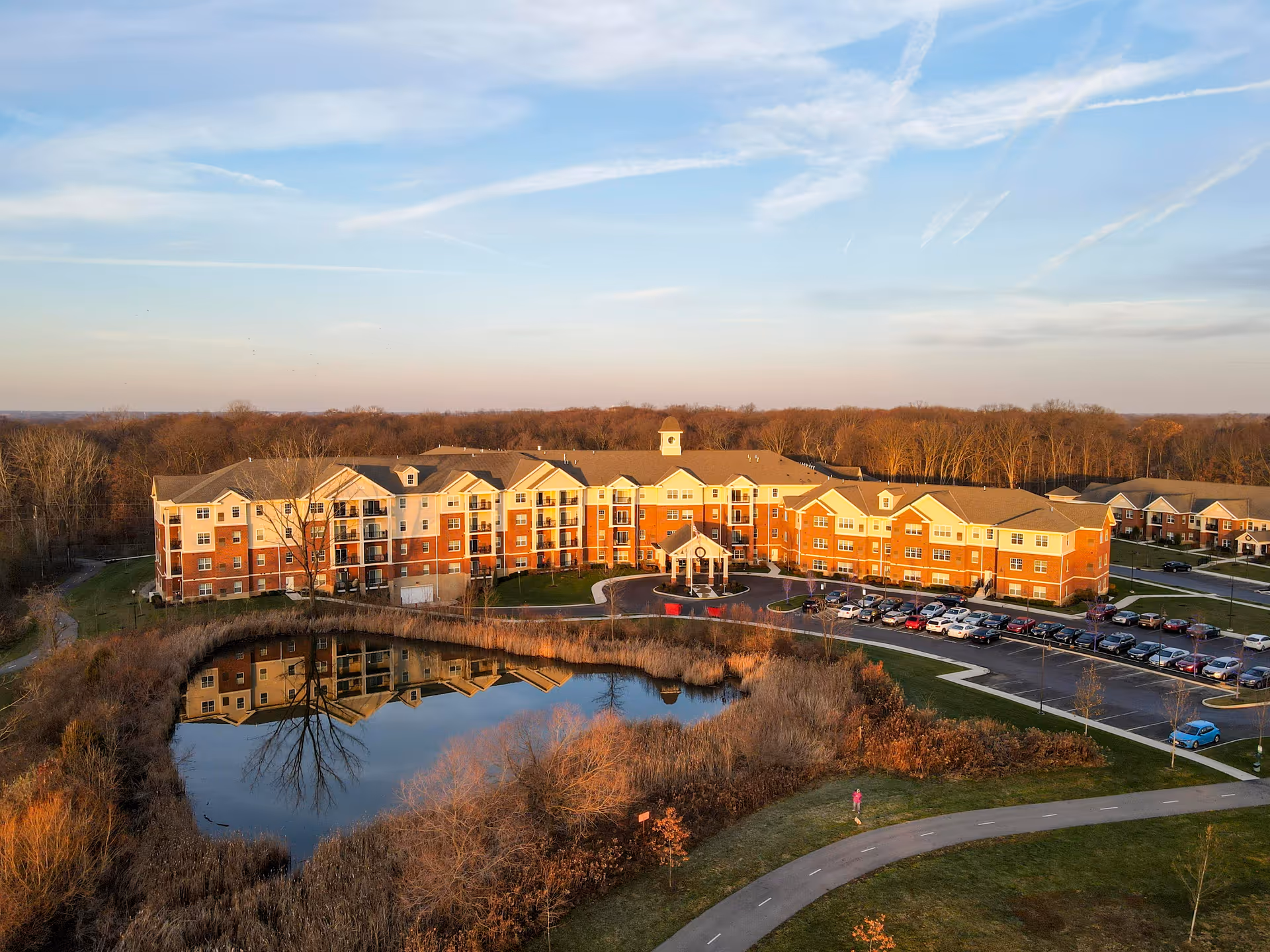 Aerial view of Inniswood Village senior living complex with pond, parking, and trees.
