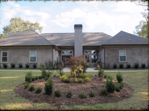 Single-story senior care facility exterior with central entrance and circular landscaped garden.