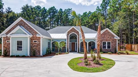 Front exterior of Coastal Cove of Wilmington, a single-story brick-and-siding senior living building with driveway.