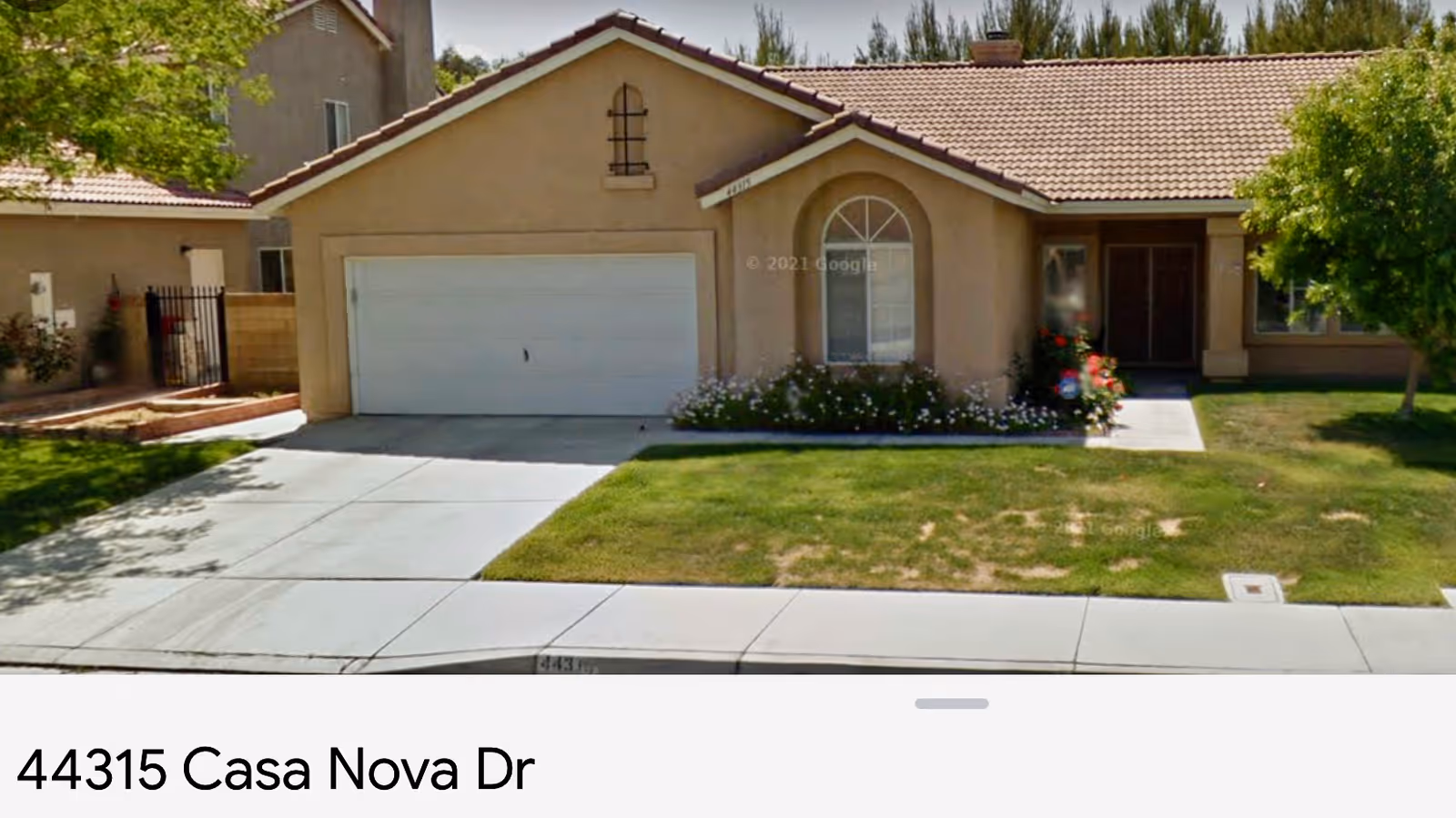 Front exterior of a single-story beige house with a two-car garage, a lawn, and a flower bed.