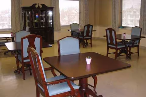 Dining room with wooden tables, chairs, and a pink plant centerpiece.