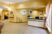 Well-lit reception lobby with a front desk, seating, decorative wall art, and patterned carpet.