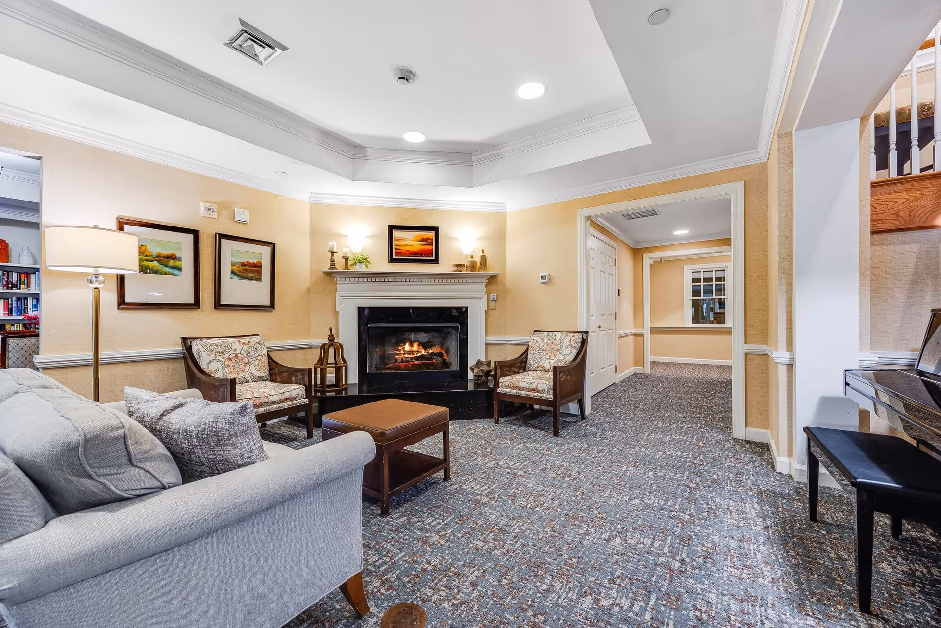 Comfortable common room with a sofa, armchairs, coffee table, fireplace, and a piano.